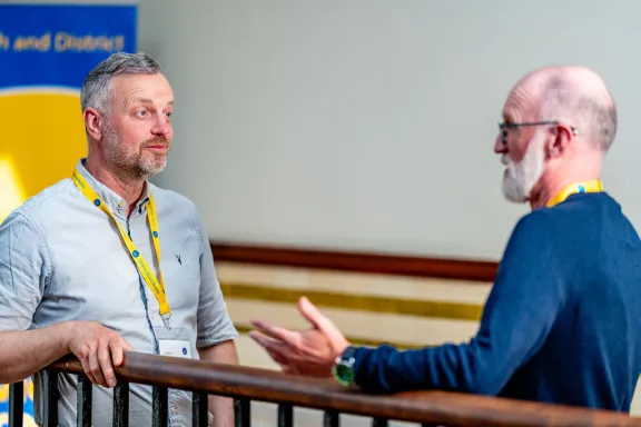 Two male volunteers talking at a railing